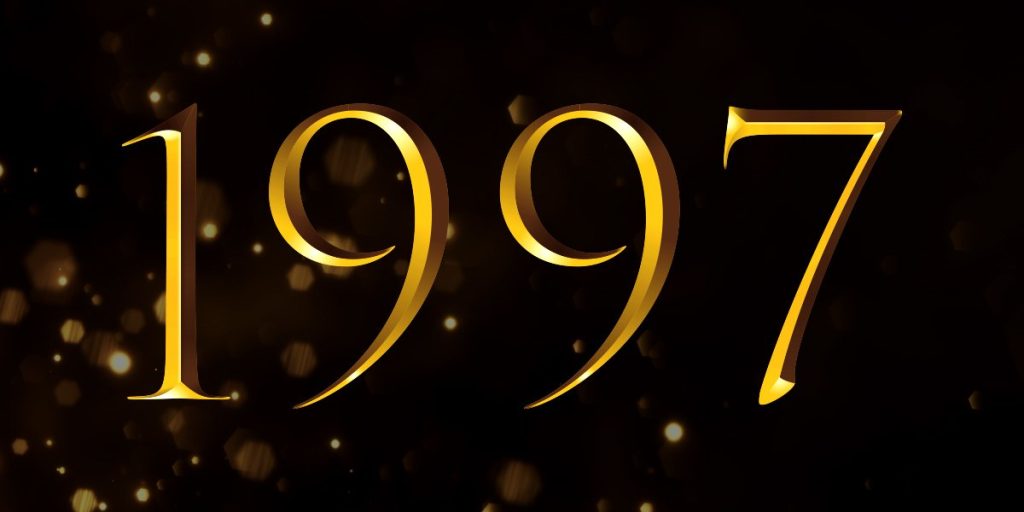 A group of elegantly dressed individuals stands on stage, holding awards, with a spotlight illuminating them.