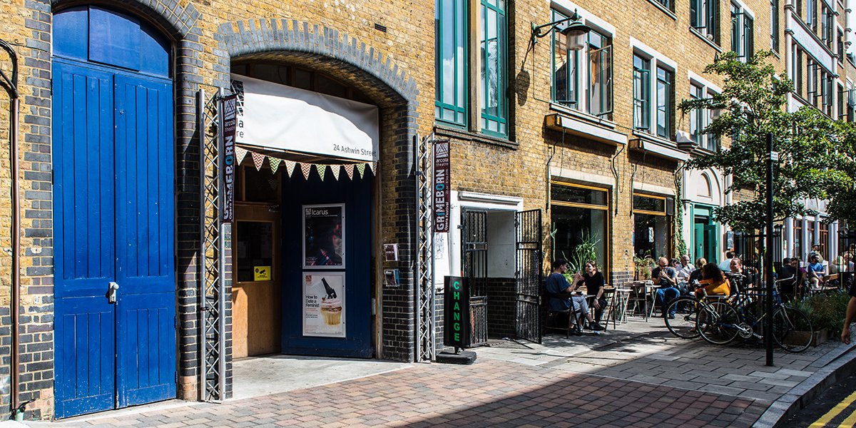 Entrance of Arcola Theatre featuring blue doors and a sunny courtyard.