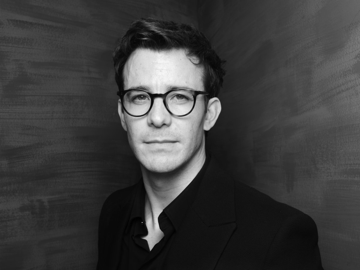 A close-up of a man wearing glasses. He is looking at the camera.