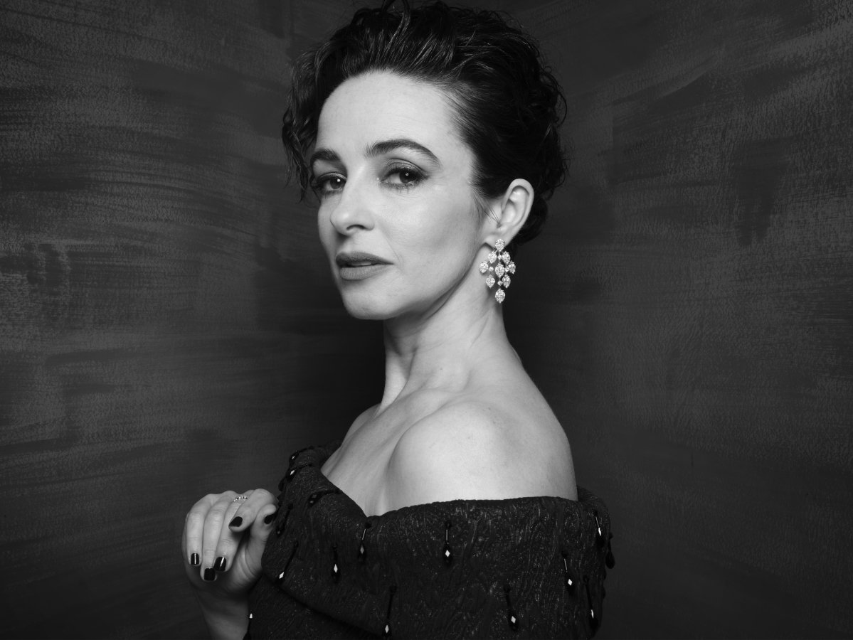 A close-up of a woman wearing big jewel earrings. She is side-on with her head turned to the camera.