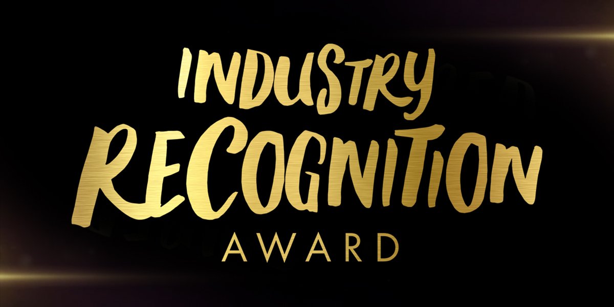 Olivier Award recipients pose together, smiling, wearing formal attire, with a backdrop featuring award logos and decorations.