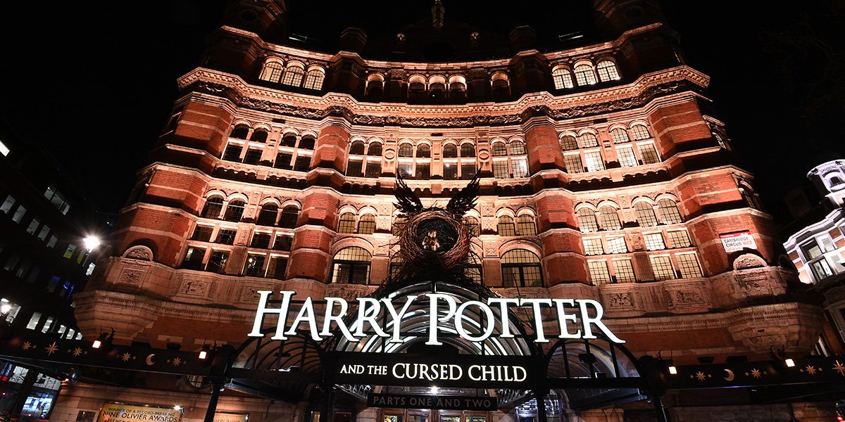 A grand palace entrance with ornate architecture, featuring intricate carvings, large doors, and lush greenery.