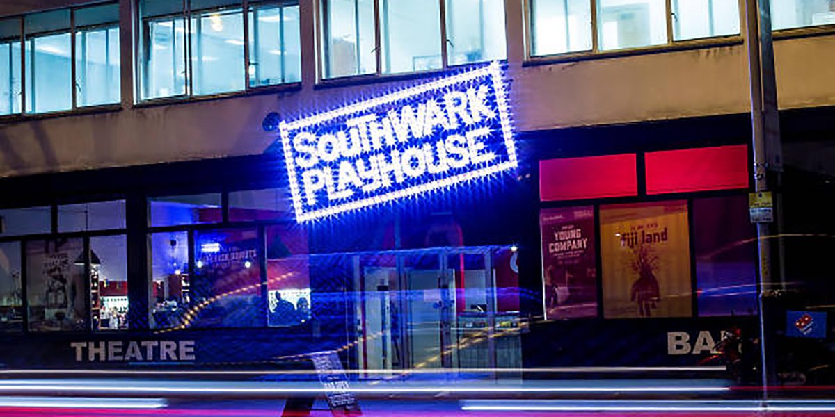 A busy street in Southwark, featuring pedestrians, shops, and a clear blue sky in the background.